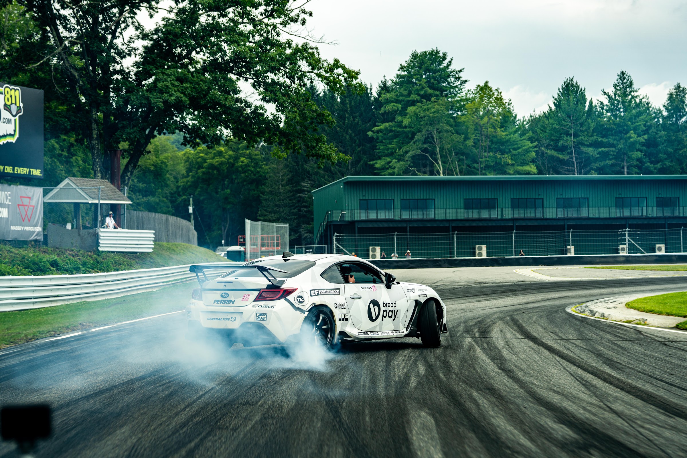 Drift car mid-slide with smoke filling the paddock behind