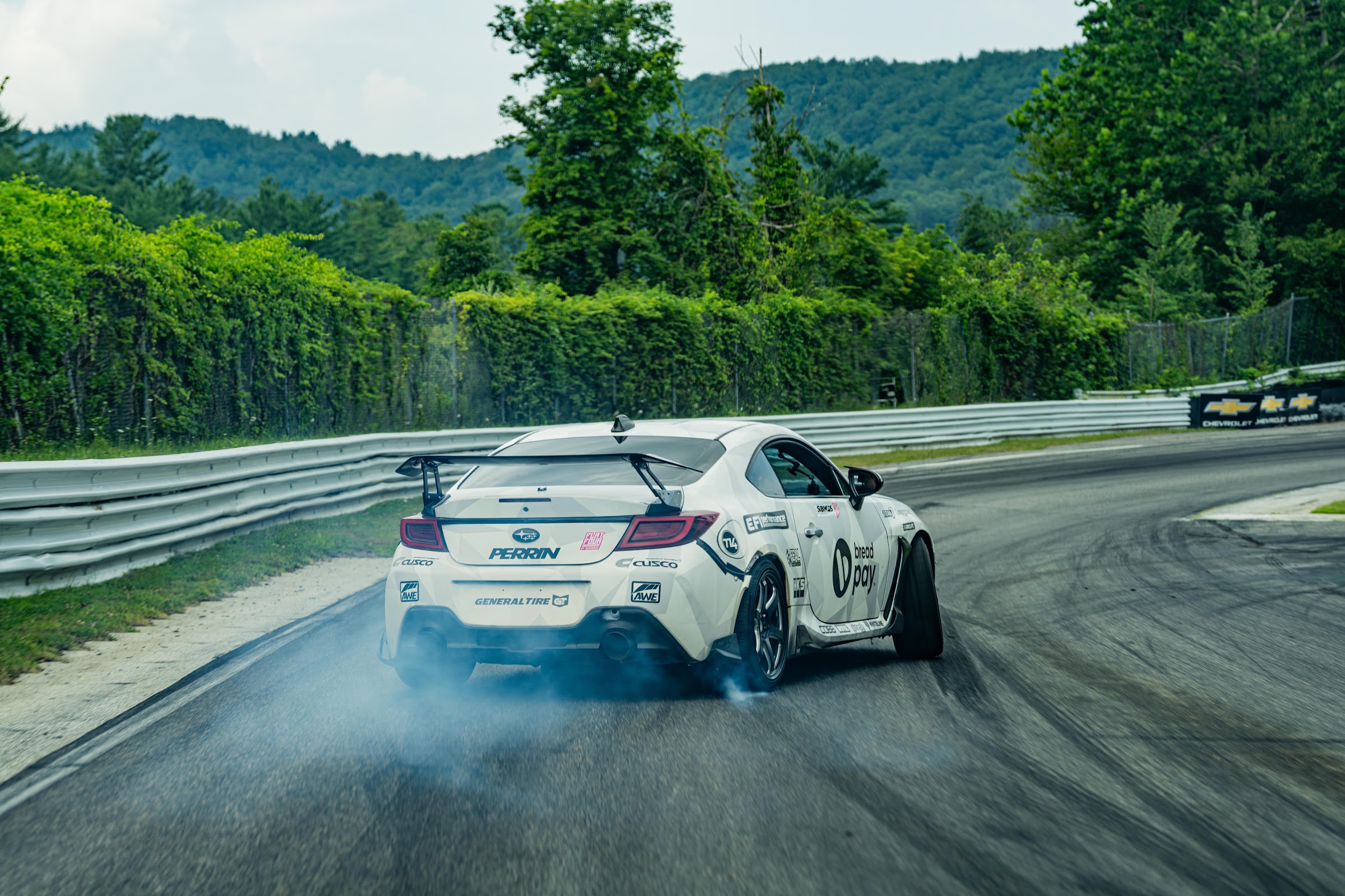 White BRZ drifting with smoke pouring off the rear tires