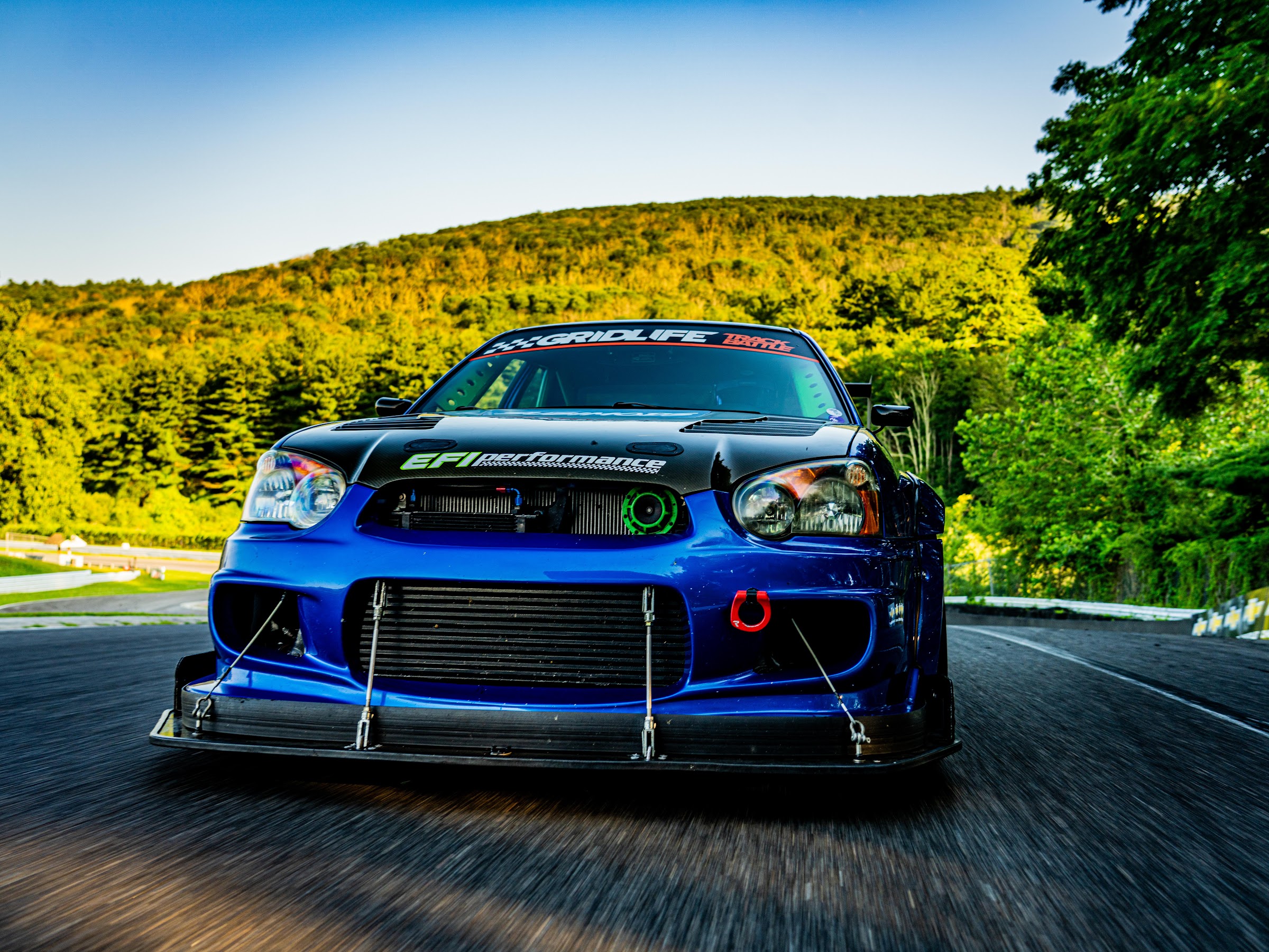 Blue STI rolling shot through green hills