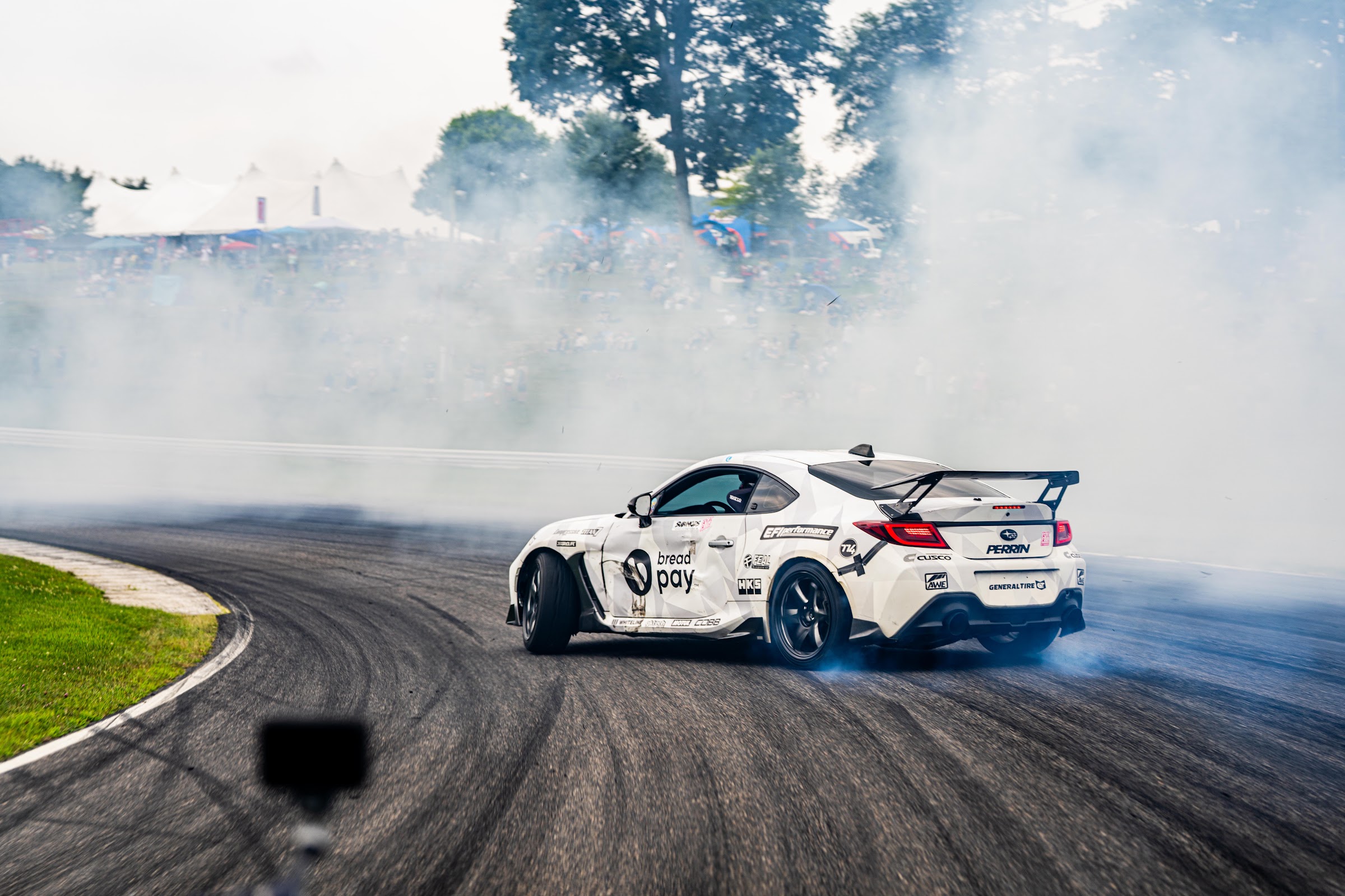 Drift car sliding through a cloud of tire smoke at Lime Rock
