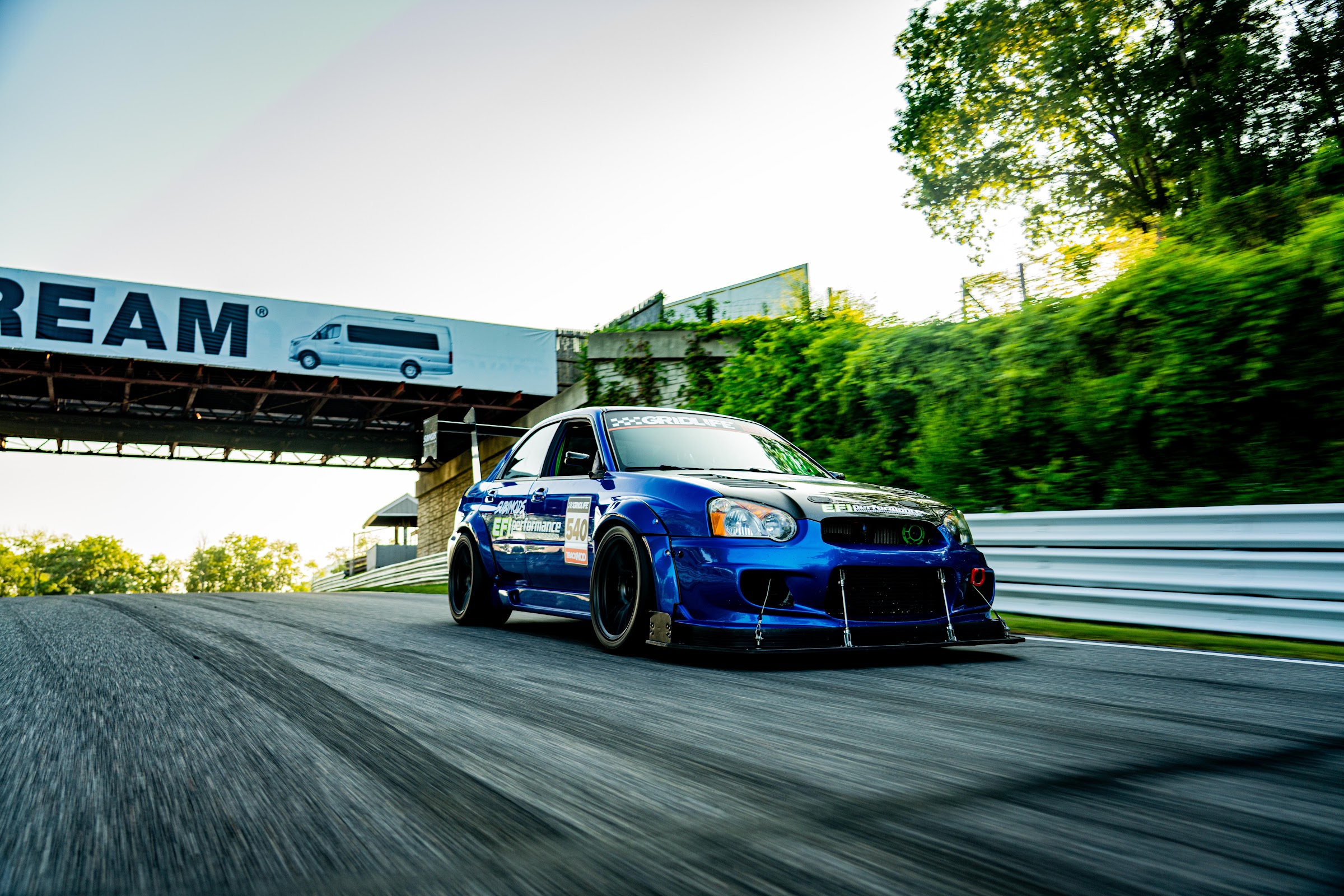 Blue STI rolling shot past the Airstream bridge
